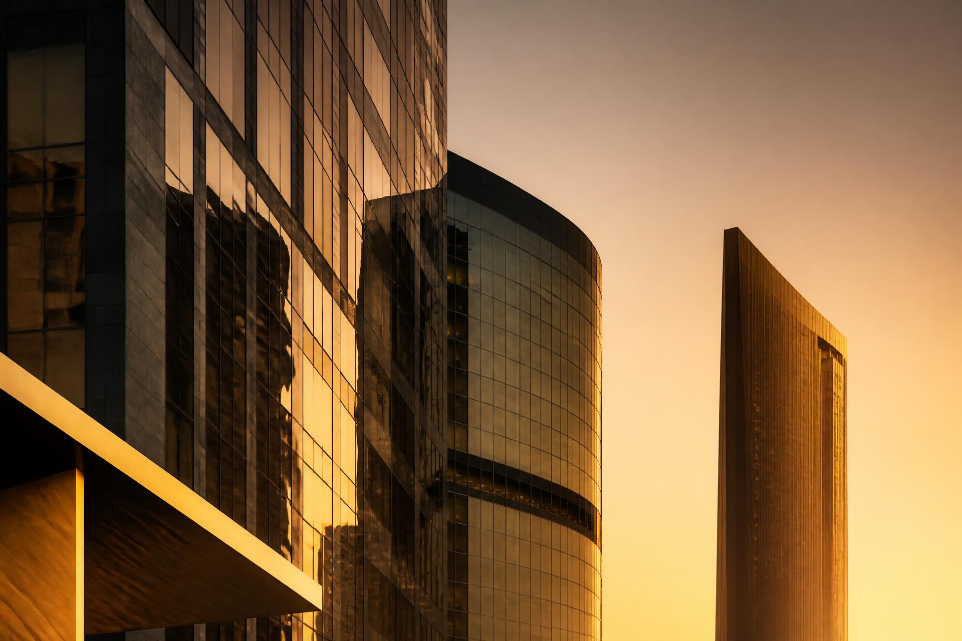 Modern glass office towers in a Gulf business district at golden hour